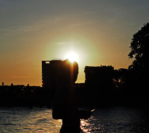 Silhouette woman by tree against sky during sunset