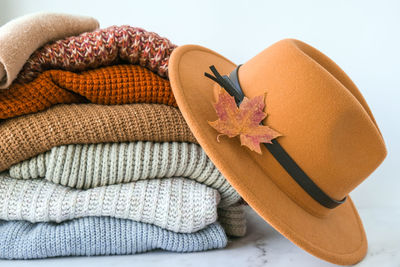 Stack of cozy knitted warm sweater with autumn fall maple leaf and beige stylish hat. sweaters 