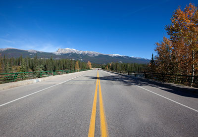 Road amidst trees and mountains against sky