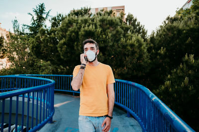 Young man using mobile phone while standing on bridge