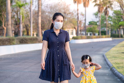 Mother and daughter wearing medical face mask prevent flu, pollution and covid 19 walking at street.