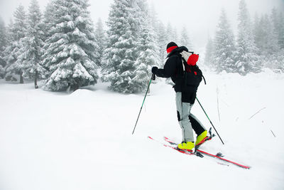 Side view of man skiing on snow covered field