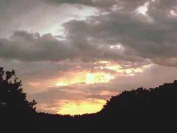 Silhouette of trees against cloudy sky