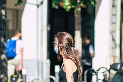 Side view of woman standing against blurred background