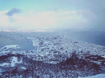 Aerial view of snow covered cityscape against sky