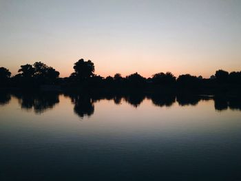 Scenic view of lake against clear sky at sunset