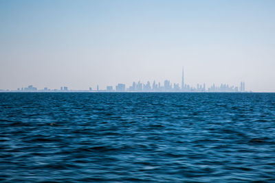 View of sea and cityscape against clear sky
