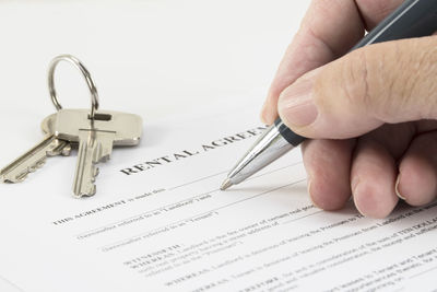 Close-up of hand filling rental agreement by house key