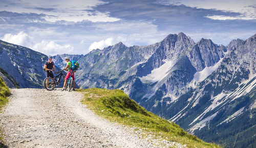 Rear view of people riding bicycle on mountain