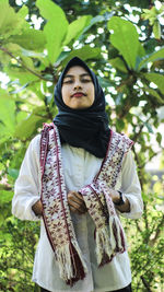 Young woman with eyes closed standing against plants