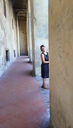 Woman standing by wall of building