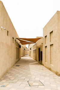 Empty alley amidst buildings against clear sky