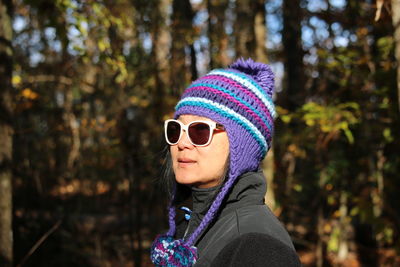 Woman wearing knit hat against trees in forest