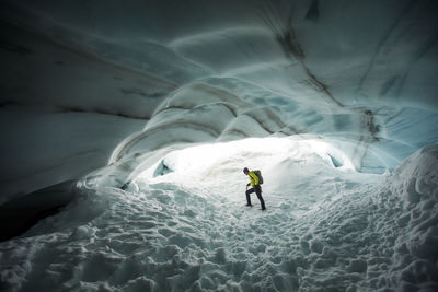 Backpacker explores the inside a glacial ice cave.