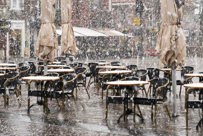 Empty chairs and tables by a restaurant, outdoors in the snow