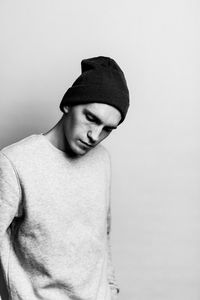 Thoughtful young man standing against white background