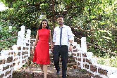 Portrait of couple moving down on steps against trees