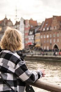 Unrecognizable tourist traveler in old town in gdansk. woman looking on riverside on granary island