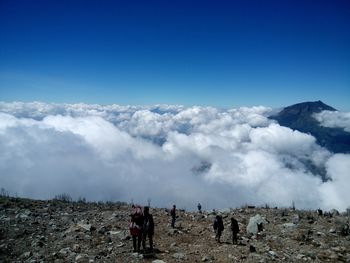 High angle view of people standing on mountain by cloudscape