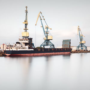 Cranes at commercial dock against sky