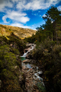 Stream flowing amidst rocks against sky