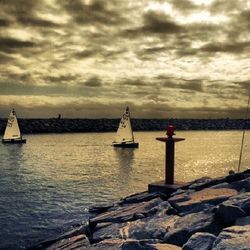 Boat sailing in sea against cloudy sky