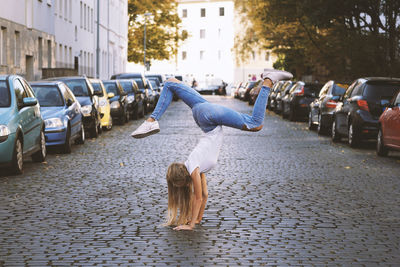 Teenage girl doing handstand on street in city