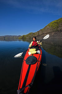 Woman rowing sea kayak on still lake in central iceland