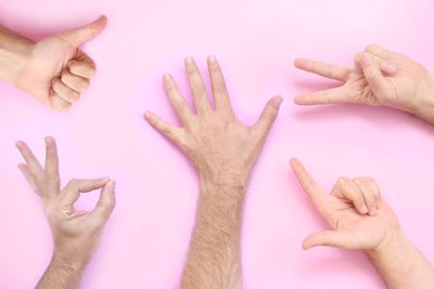 Cropped image of people gesturing over pink background