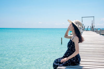 Side view of young woman in sea against sky