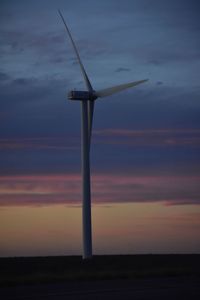 Wind turbine against sky during sunset