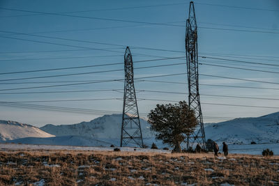 Electricity pylon on field against sky during winter