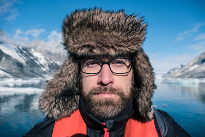 Portrait of mid adult man against lake during winter