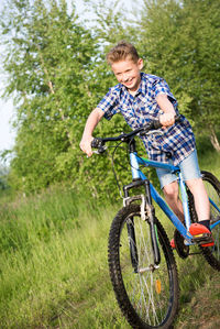 Smiling boy cycling on grassy field