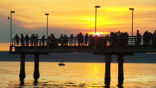 Silhouette pier over sea against sky during sunset