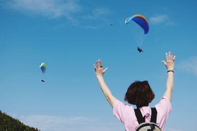 Rear view of women flying against sky