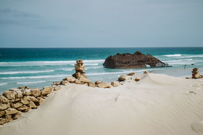 Scenic view of rocks on beach against sky