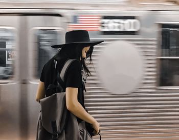 Girl with blurred motion of train at subway station in the back 