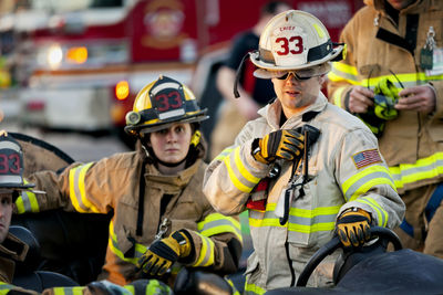 Firefighter holding walkie-talkie while standing by coworkers