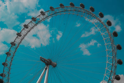 Low angle view of ferris wheel against cloudy sky