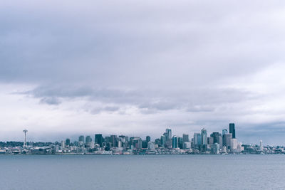 City at waterfront against cloudy sky