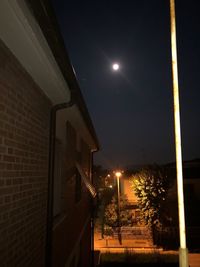 Low angle view of illuminated street light against building at night