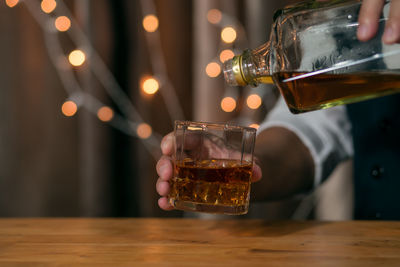 Close-up of hand pouring wine in glass on table