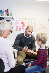 Grandmother looking at grandson being examined by orthopedic surgeon in clinic