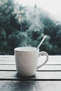 Close-up of steam emitting from coffee cup on table