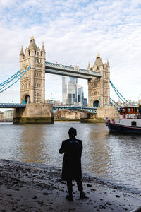 Rear view of man standing on bridge over river