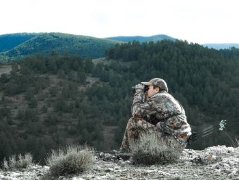 Full length of soldier sitting on mountain against sky