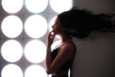 Portrait of young woman looking away against wall