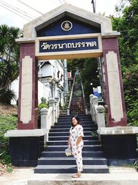 Smiling mid adult woman standing against entrance gate