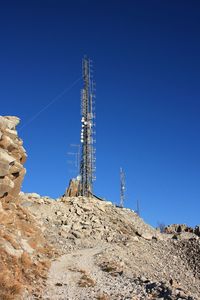 Low angle view of communications tower against clear blue sky